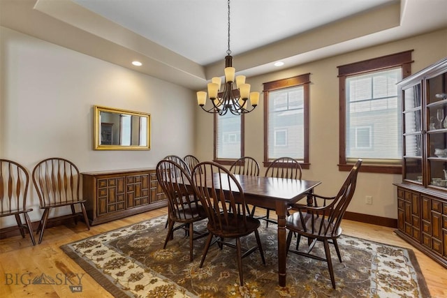 dining room with an inviting chandelier, hardwood / wood-style flooring, and a raised ceiling