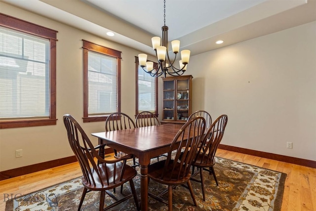 dining space featuring an inviting chandelier, wood-type flooring, and a raised ceiling