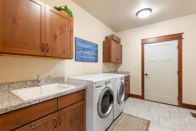 clothes washing area featuring sink, light tile patterned floors, cabinets, and washing machine and clothes dryer