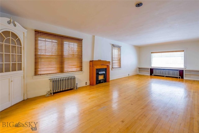 324 N 5th St, Livingston, MT 59047 - unfurnished living room with radiator heating unit, hardwood / wood-style floors, and a fireplace