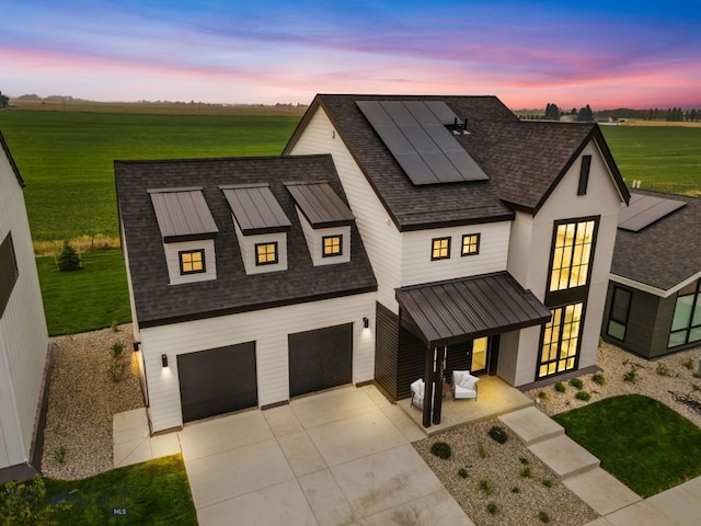 view of front of home with a garage, solar panels, and a yard