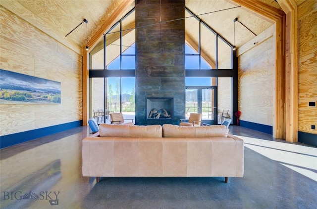 unfurnished living room with high vaulted ceiling, a large fireplace, and concrete flooring