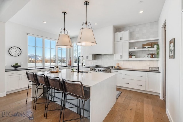 kitchen featuring an island with sink, sink, white cabinets, and a breakfast bar area