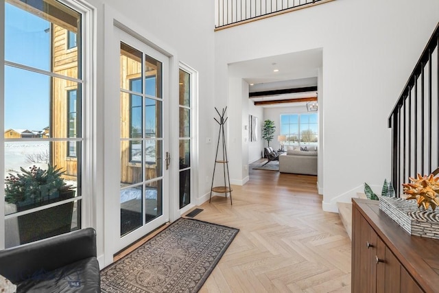 doorway to outside featuring a high ceiling, light parquet flooring, and beam ceiling