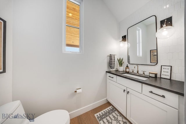 bathroom featuring hardwood / wood-style flooring, vanity, toilet, and lofted ceiling