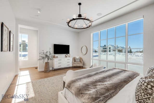 bedroom with light hardwood / wood-style floors and an inviting chandelier