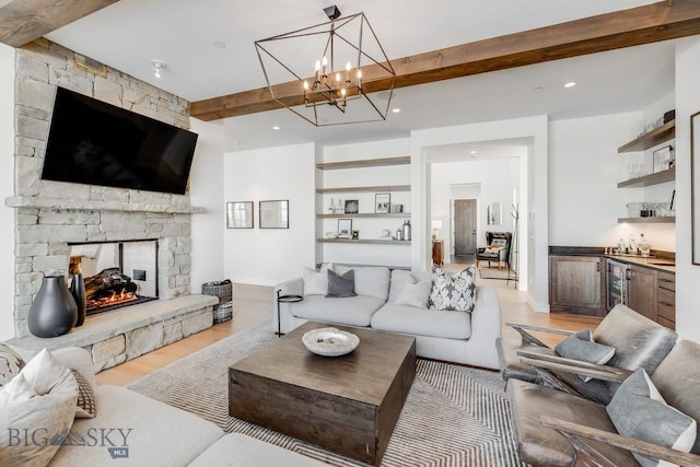 living room with light wood-type flooring, indoor bar, a stone fireplace, and beam ceiling