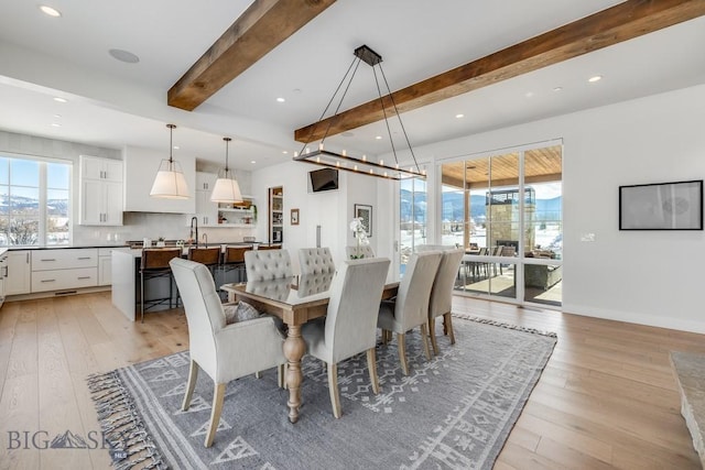 dining room with light wood-type flooring, beamed ceiling, and sink