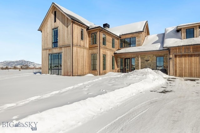 snow covered rear of property with a mountain view