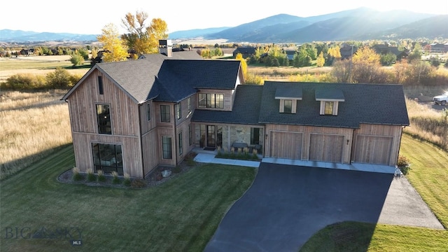 view of front of property featuring a mountain view, a front yard, and a garage