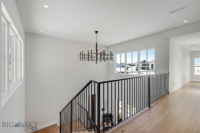 hall with light hardwood / wood-style floors and a chandelier