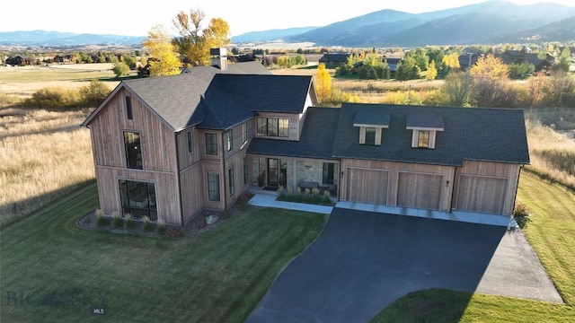 view of front of property featuring a mountain view, a front yard, and a garage