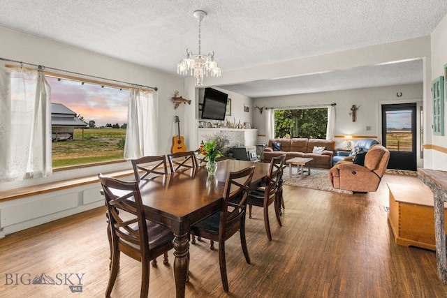 dining area with an inviting chandelier, wood-type flooring, and a textured ceiling