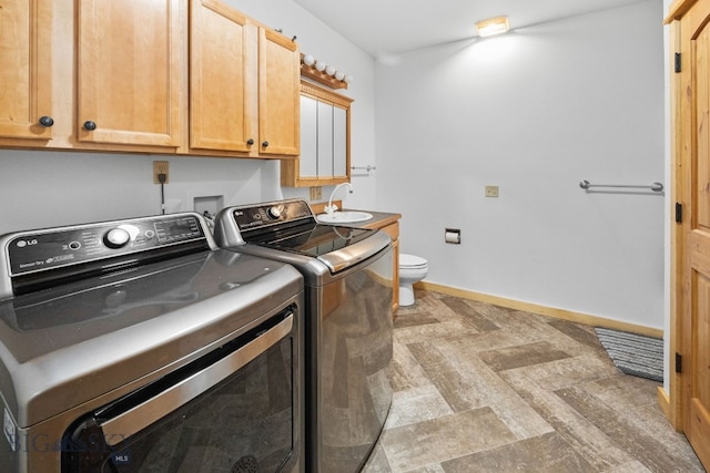 clothes washing area with washing machine and clothes dryer, a sink, laundry area, and baseboards