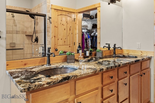 full bath featuring a sink, double vanity, and tiled shower