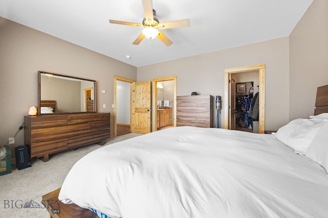 carpeted bedroom with a walk in closet, ceiling fan, and connected bathroom
