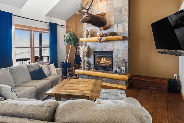 living area featuring dark wood-style floors, vaulted ceiling, and a fireplace