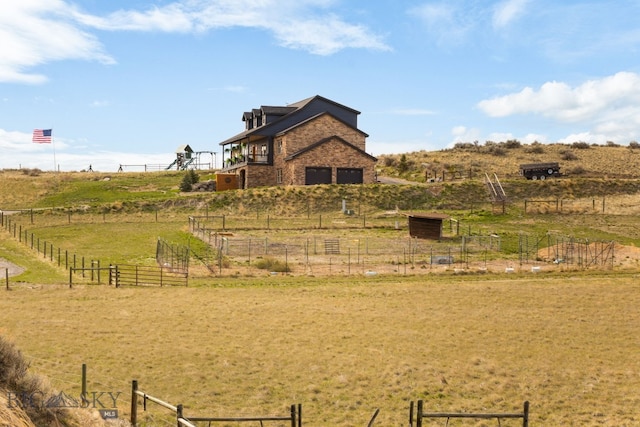 exterior space featuring a rural view, a garage, and fence