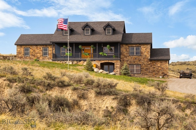 view of front facade featuring roof with shingles and stone siding