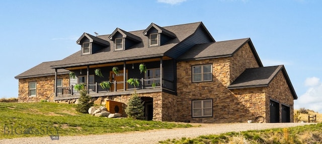 view of front facade with an attached garage, stone siding, and covered porch