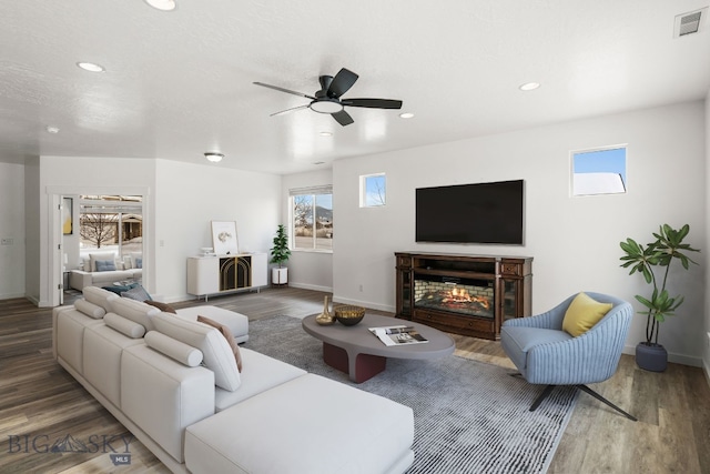 living room with recessed lighting, visible vents, wood finished floors, and a glass covered fireplace