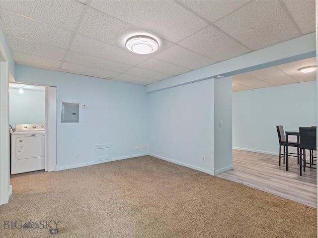 finished below grade area featuring a paneled ceiling, washer / dryer, electric panel, and carpet flooring