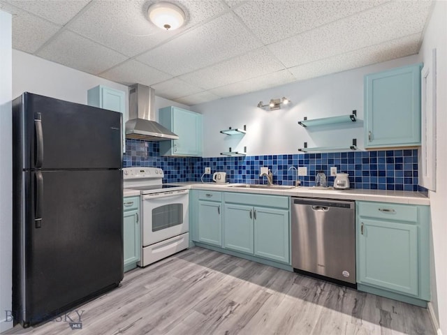 kitchen with wall chimney exhaust hood, freestanding refrigerator, light countertops, white electric range, and stainless steel dishwasher