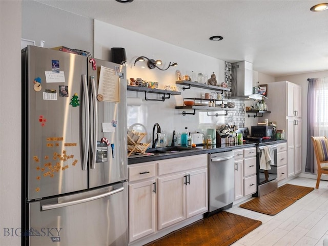 kitchen featuring white cabinets, dark countertops, appliances with stainless steel finishes, open shelves, and a sink