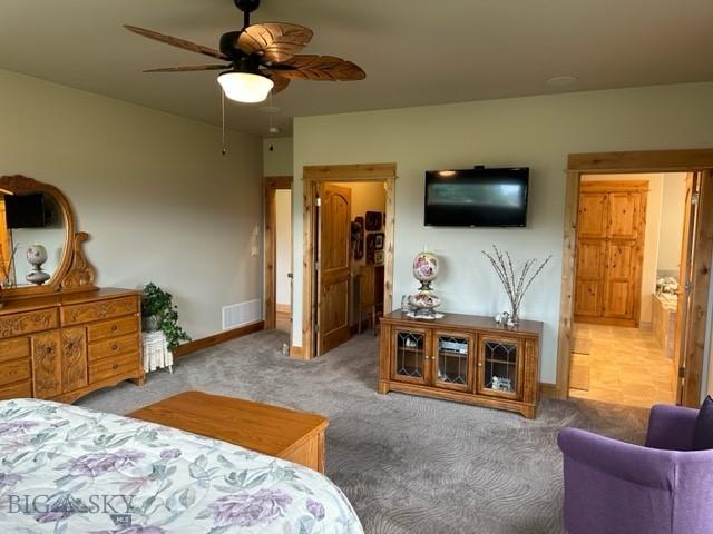 bedroom with carpet floors, visible vents, ceiling fan, ensuite bath, and baseboards