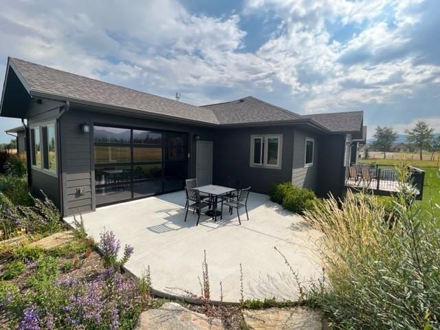 back of property featuring roof with shingles and a patio