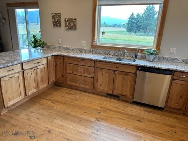 kitchen with dishwasher, light stone counters, a sink, and light wood-style flooring