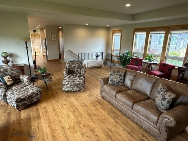 living room with light wood-style flooring, a raised ceiling, and recessed lighting