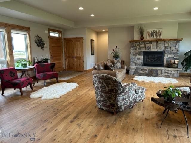 living room featuring light wood-style floors, a stone fireplace, and recessed lighting