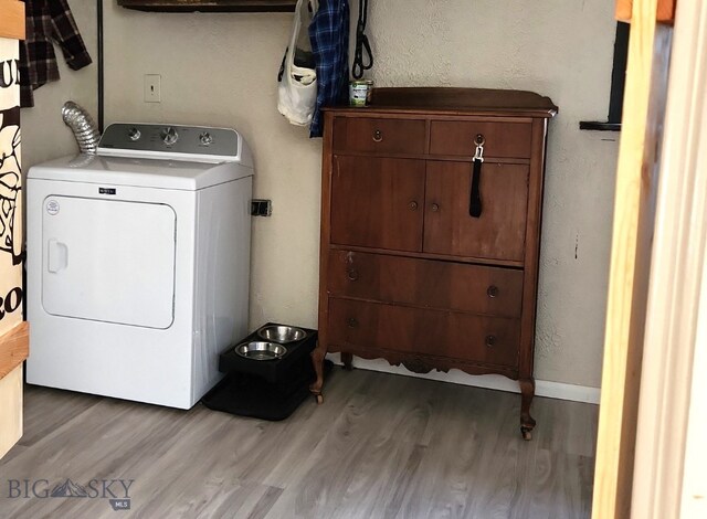 laundry area with washer / dryer, light wood-style flooring, a textured wall, and baseboards