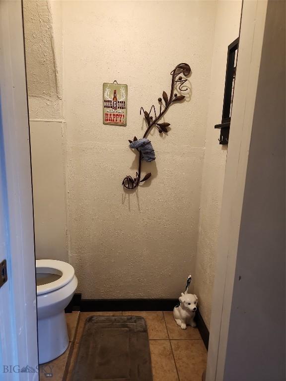 bathroom featuring tile patterned floors, toilet, and a textured wall