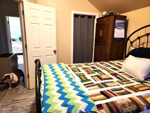 bedroom with wood finished floors and vaulted ceiling