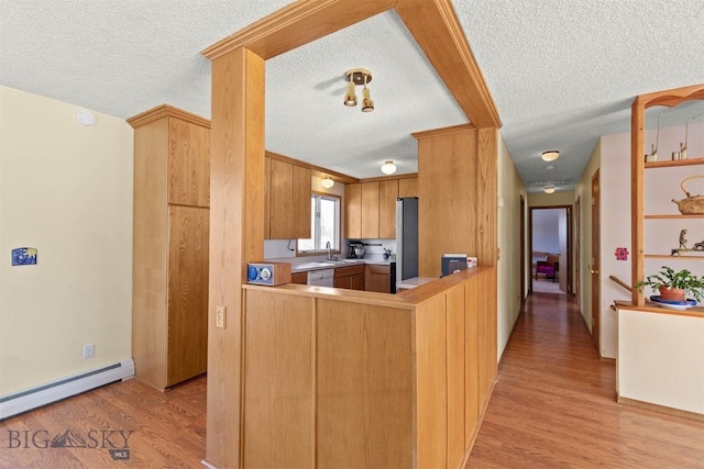 kitchen with a baseboard heating unit, a textured ceiling, light wood-type flooring, dishwasher, and a peninsula