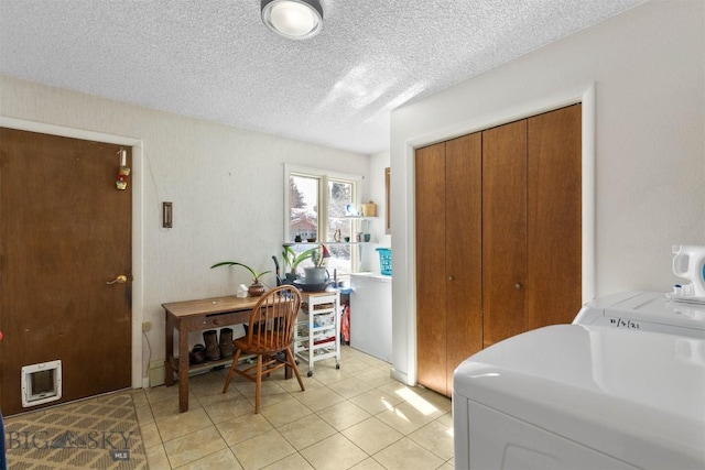 interior space with light tile patterned floors, laundry area, washer and clothes dryer, and a textured ceiling