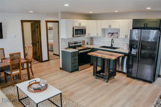 kitchen featuring light wood-style flooring, stainless steel appliances, light countertops, white cabinetry, and a sink