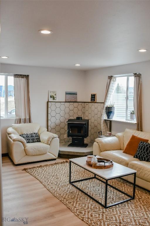 living room with recessed lighting, a wood stove, plenty of natural light, and wood finished floors