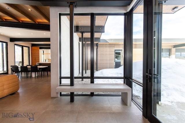 doorway to outside featuring beamed ceiling