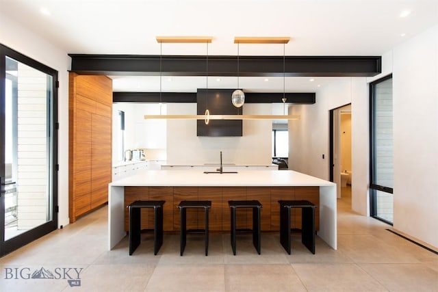 kitchen featuring a large island, light countertops, hanging light fixtures, a sink, and a kitchen breakfast bar