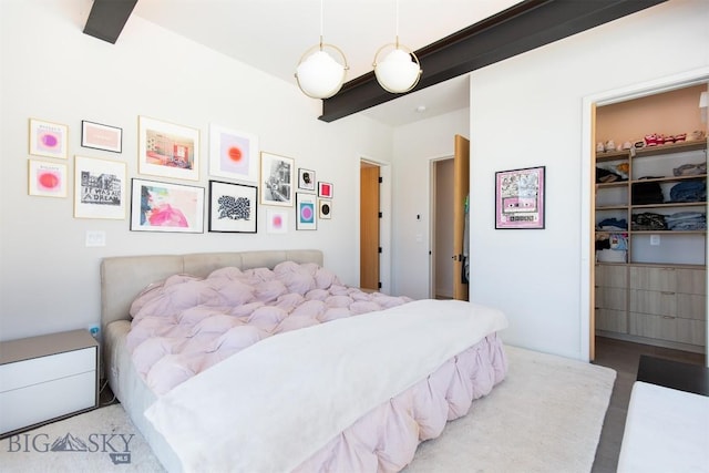 bedroom with a closet, beamed ceiling, and a walk in closet