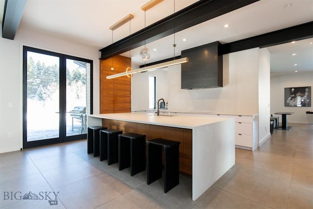 kitchen featuring modern cabinets, light countertops, white cabinetry, pendant lighting, and a sink