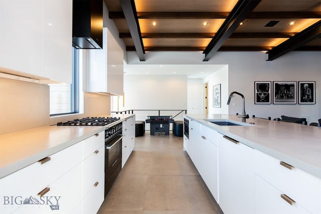 kitchen with high end stove, white cabinetry, light countertops, and a sink