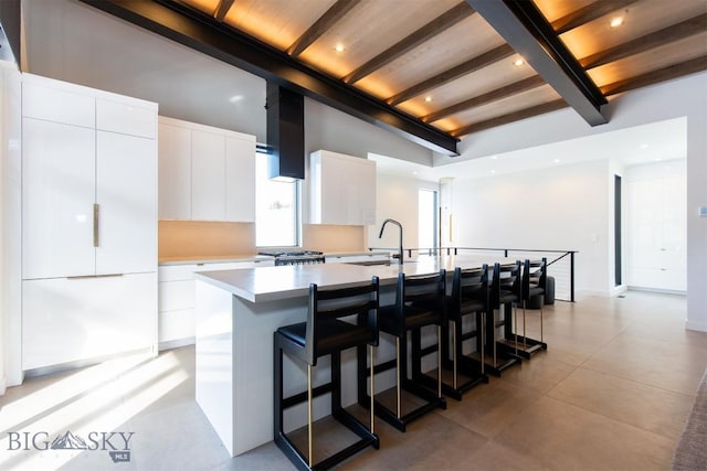 kitchen with light countertops, a kitchen island with sink, a sink, white cabinetry, and modern cabinets