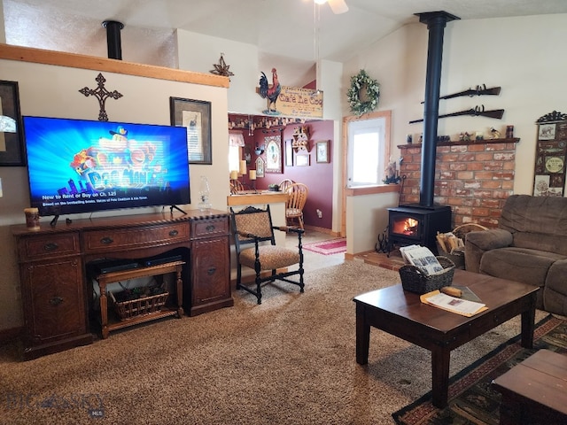 living area featuring lofted ceiling, a wood stove, carpet flooring, and ceiling fan