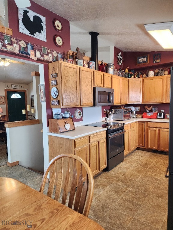 kitchen with a textured ceiling, ceiling fan, light countertops, electric stove, and stainless steel microwave