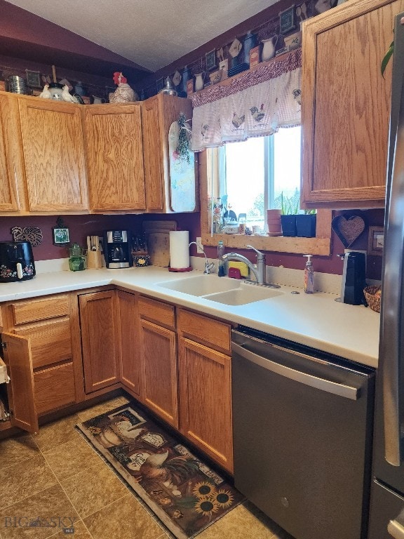 kitchen with brown cabinetry, appliances with stainless steel finishes, light countertops, and a sink