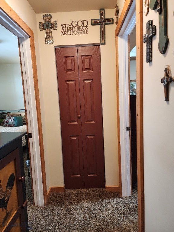 hallway with baseboards and dark colored carpet